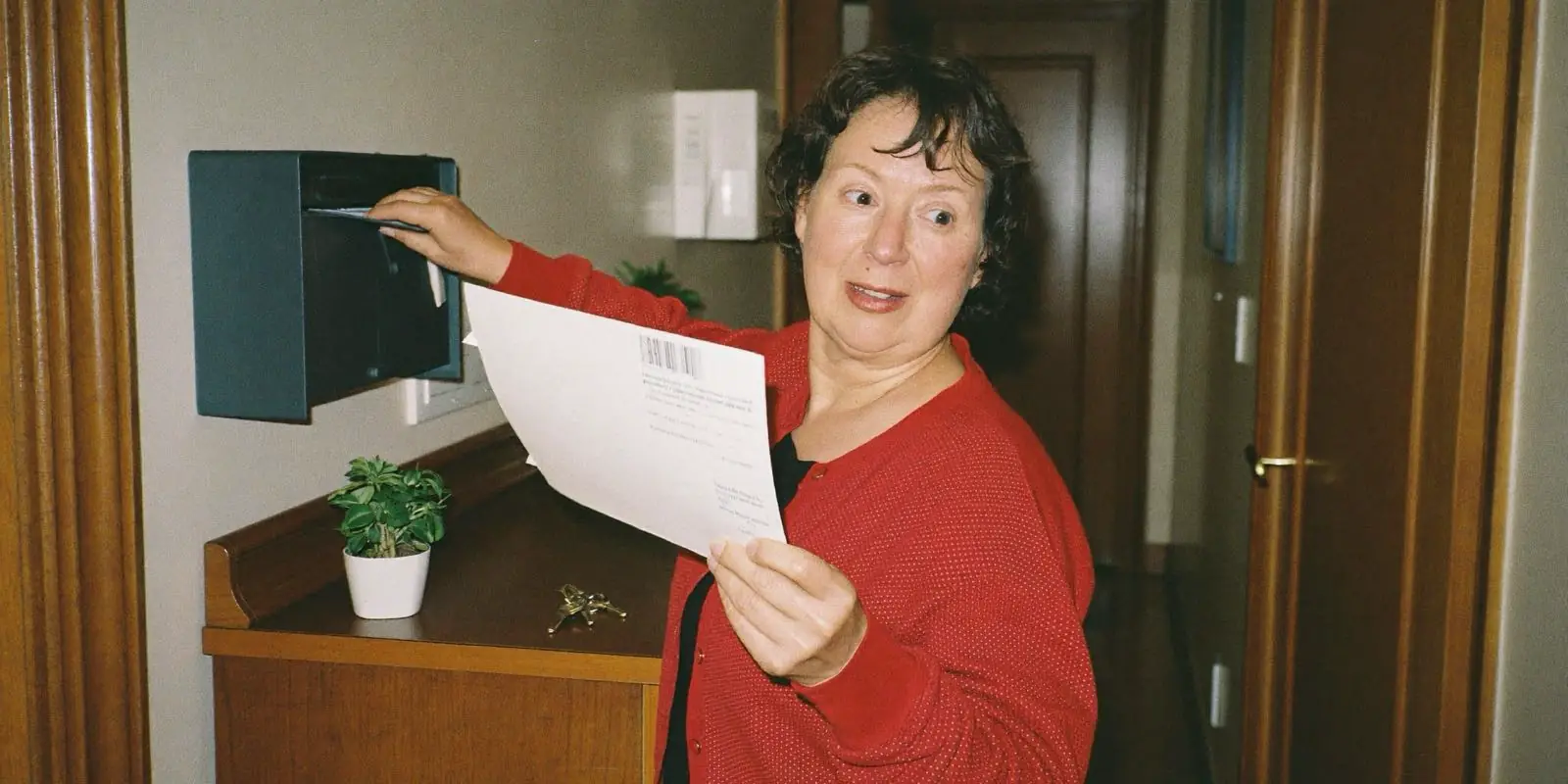 Frau öffnet im Flur einen amtlichen Brief